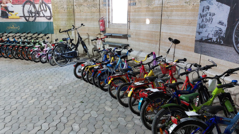 Gebrauchte Kinderfahrräder: Sehr viele bunte Kinderfahrräder entlang einer Betonwand